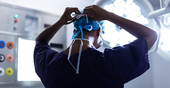 Doctor at a hospital tying their surgical mask