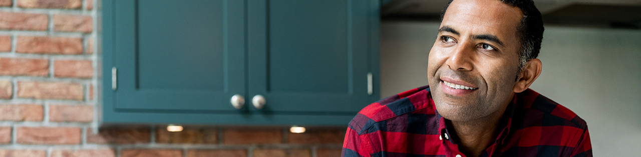 man sitting in his kitchen looking happy because he just claimed compensation