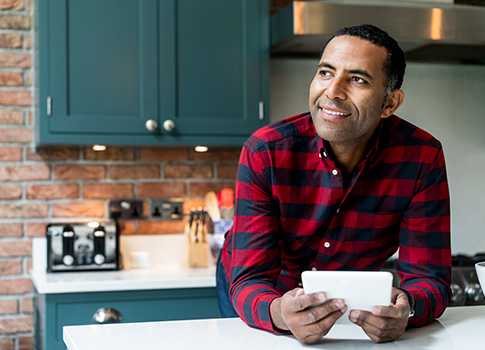 man sitting in his kitchen looking happy because he just claimed compensation