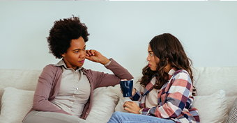 two women sitting on sofa talking to each other
