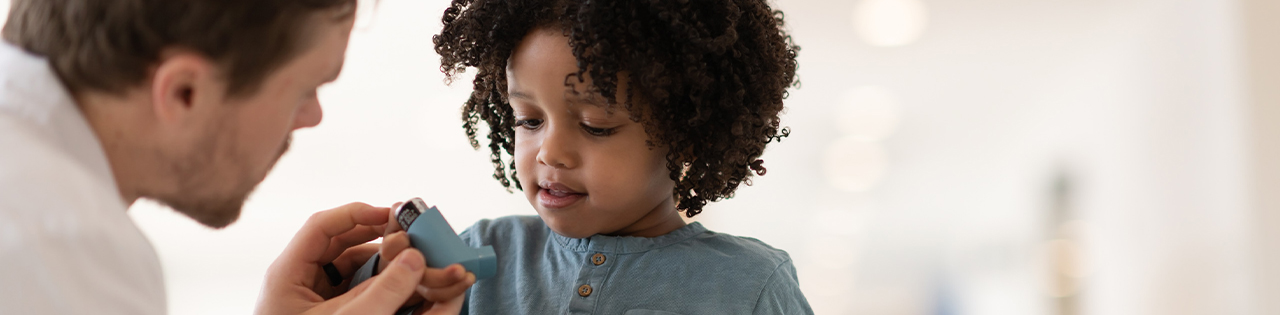 Father helping his child with using their asthma inhaler