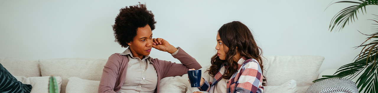 two women sitting on sofa talking to each other