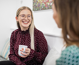 Yazmin Griffiths, Paralegal at Medical Accident Group sitting on a sofa with a cup of tea laughing