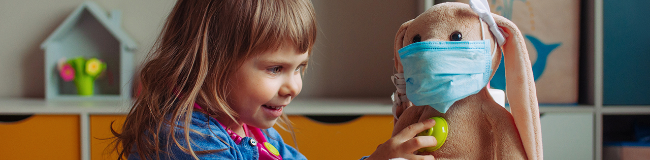 Girl pretending to be a doctor consulting a teddy bear