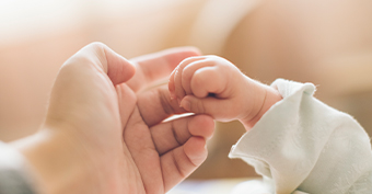 Mother holding her newborn child's hand