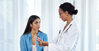 Doctor speaking to patient about patient's concerns over unsafe independent cosmetic surgery in a doctors office