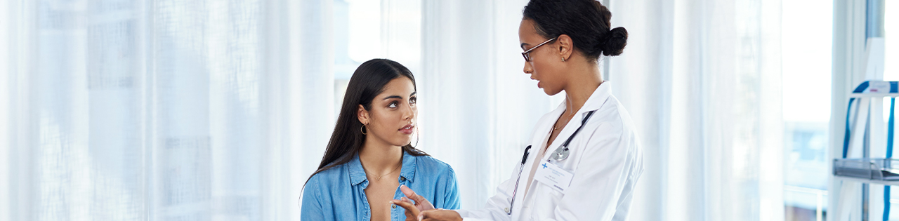 Doctor speaking to patient about patient's concerns over unsafe independent cosmetic surgery in a doctors office