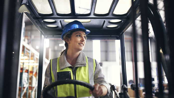 Construction worker driving truck wearing a blue helmet and jacket at construction site