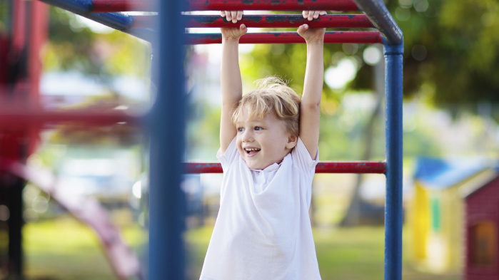 Child handing from hag bars in outdoor playground