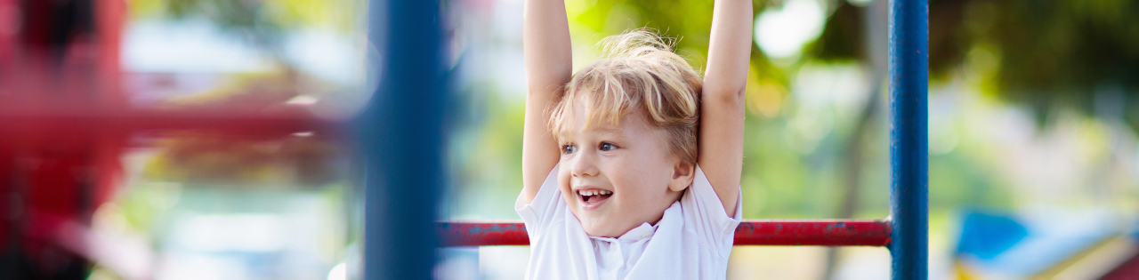 Child handing from hag bars in outdoor playground