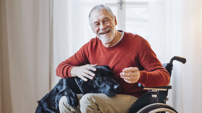 Elderly mean in a wheelchair with his cute black god in his lap smiling despite suffering from brain injury