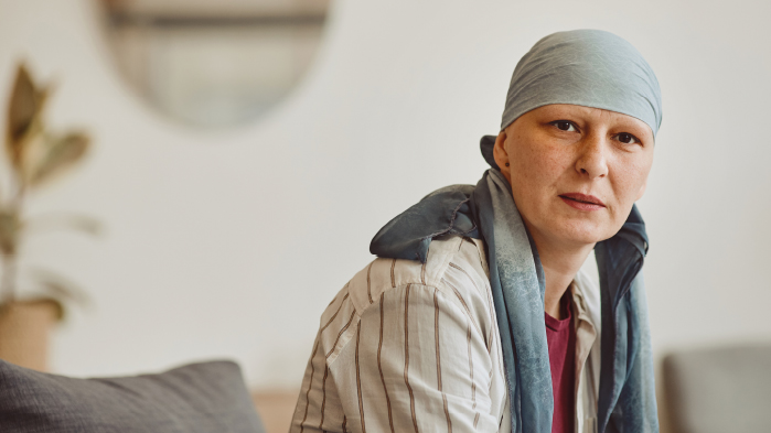 Lady suffering from cancer sitting down on sofa
