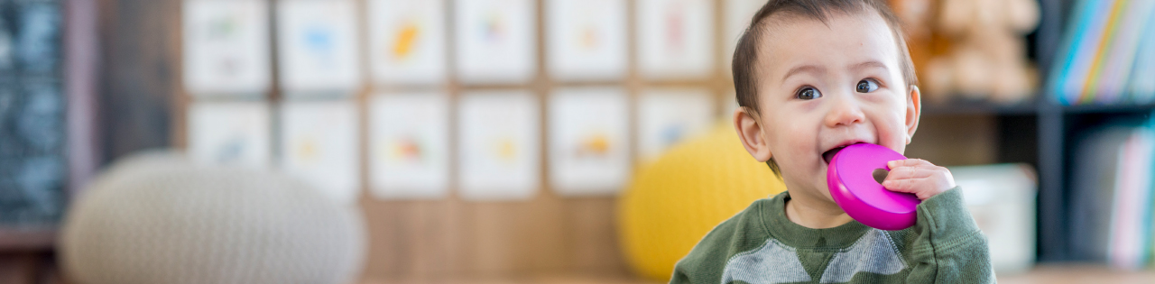 Cute child holding pink disc near their mouth