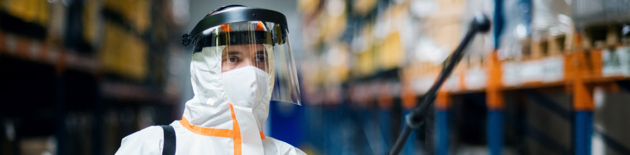 Person in hazmat suit with face covering in industrial park trying to remove industrial disease