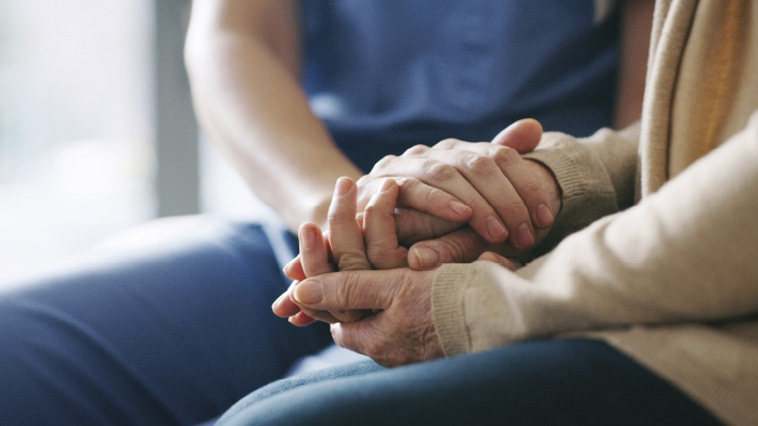 Nurse is holding patient's hands who is suffering from sepsis, to calm the patient