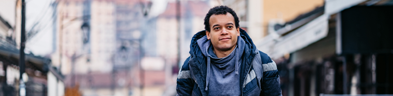 Disabled person wearing hoodie and coat standing with crutches outdoors