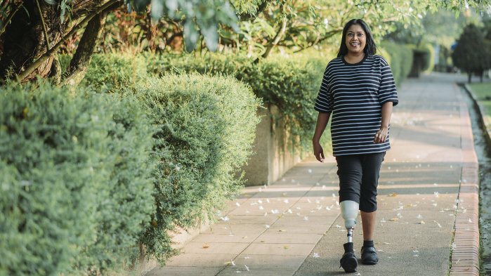 Person with prosthetic leg walking on outdoor path after having suffered from personal injury