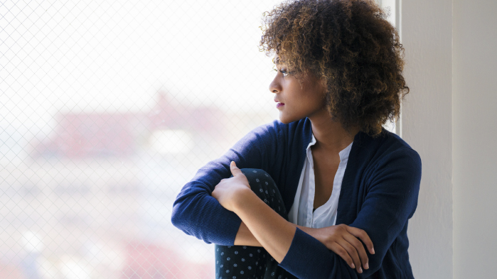 Woman looking outside through a window who is a victim of sexual misconduct