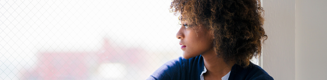 Woman looking outside through a window who is a victim of sexual misconduct