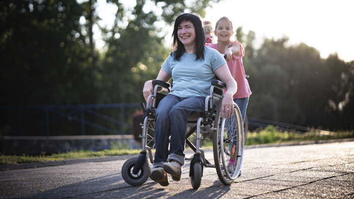 Daughter pushing mother who is in a wheelchair after she has suffered from spinal injury