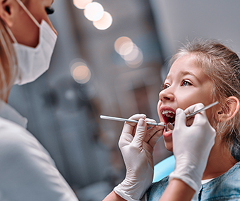 Dentist looking at teeth of little girl at dental practice