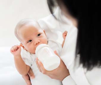 Mother feeding her baby with bottle of milk