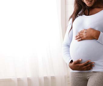 Pregnant woman holding stomach worrying afer medical negligence led to an unplanned pregnancy