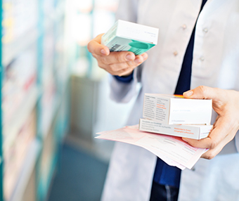 Pharmacist holding miedication at a pharmacy about to prescribe the medicaation