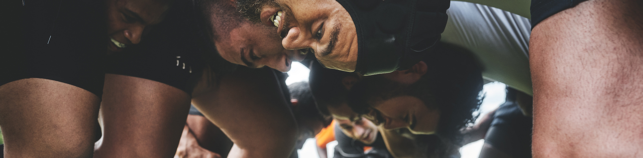 Men in a rugby scrum playing rugby on a rugby field